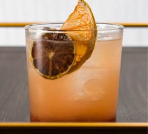 Photo of Paloma-Ha cocktail with tequila, raspberry grapefruit jam, lime juice, and Fever Tree grapefruit tonic. Served on ice in rocks glass.