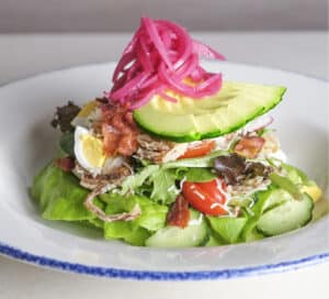 Photo of the Market Salad with mixed greens, radish, cucumber, carrot, cherry tomato, chopped egg, croutons, parmesan, white balsamic dressing.