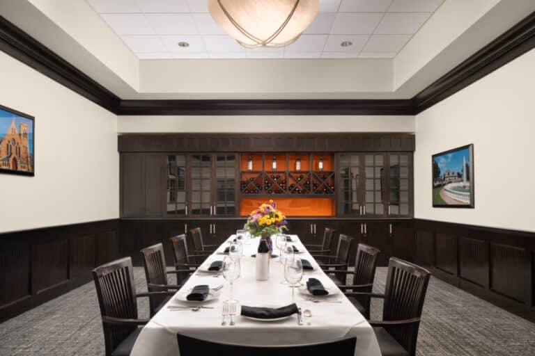 long table set for eight people with flowers and wine glasses in a private dining area