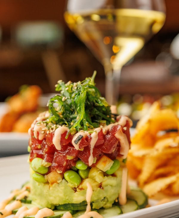 tuna poke dish and a glass of wine on a table